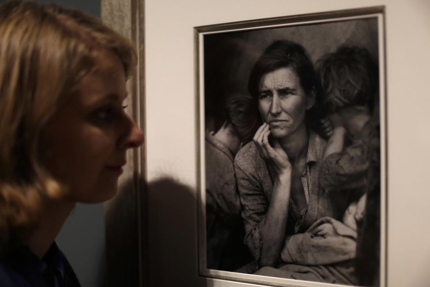 A Tate member of staff poses next to American photographer Dorothea Lange's "Migrant Mother", from 1936, at the press view of "The Radical Eye: Modernist Photography from the Sir Elton John Collection" exhibition at the Tate Modern gallery in London, Tuesday, Nov. 8, 2016. British musician Elton John's collection of international modernist photography from the 1920s to 50s includes almost 200 prints and opens to the public on November 10. (AP Photo/Matt Dunham)