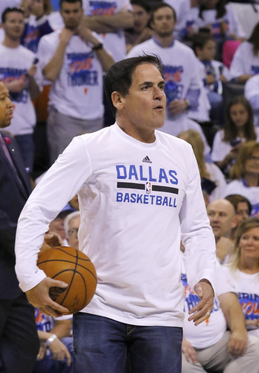 This April 16, 2016 photo shows Dallas Mavericks owner Mark Cuban watching his team warm up before the start of Game 1 of a first-round NBA basketball playoff series in Oklahoma City. Cuban says his decision to revoke the credentials of two ESPN writers who cover his team was driven partly by concern that automated game reports could eventually replace human-generated content. Cuban said Monday, Nov. 7, 2016 that he banned Marc Stein and Tim MacMahon from Mavericks home games to bring attention to the issue of companies using automation in sports coverage. (AP Photo/Alonzo Adams)