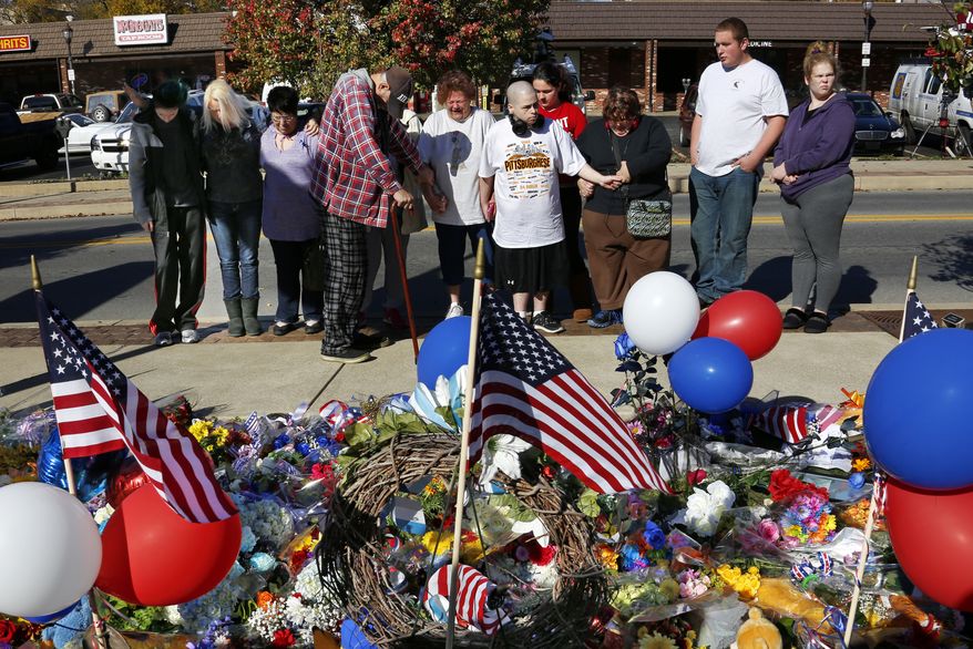 A group prays in front of a makeshift memorial for the Canonsburg Police officers who were shot when they responded to a domestic call early Thursday, Nov 10, 2016, in Canonsburg, Pa. A gunman with a history of domestic abuse shot at police officers before he and a woman were found dead following a reported fight at their apartment, authorities said. (AP Photo/Gene J. Puskar)