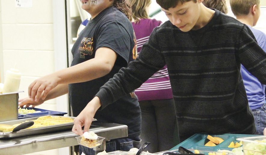 Brandon Rice, right, picks up an apple crisp from the Thermopolis Middle School lunch room. The apple crisp was made from apples picked by students in the farm to school program and served on Halloween. (Tesia Galvan/Northern Wyoming Daily News via aP)