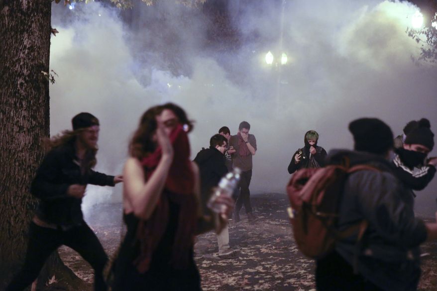Police in downtown Portland, Ore., attempt to disperse people protesting the election of President-elect, Donald Trump, Friday, Nov. 11, 2016. In Portland, police used tear gas and flash-bang grenades Friday to try to disperse the crowd after hundreds of people marched through the city, disrupting traffic and spray-painting graffiti. Authorities said "burning projectiles" were thrown at police and vandalism and assault had taken place during the rally, which organizers had billed as peaceful earlier in the day. (Stephanie Yao Long/The Oregonian via AP)