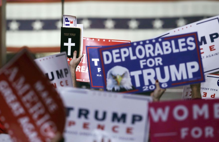 In this Monday, Nov. 7, 2016 file photo, supporters hold signs and a copy of the Bible during a rally for Republican presidential candidate Donald Trump in Manchester, N.H. (AP Photo/Charles Krupa)