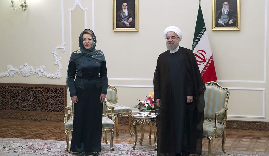 In this photo released by official website of the office of the Iranian Presidency, President Hassan Rouhani, right, stands with Russian Federation Council Speaker Valentina Matviyenko after welcoming her as he waits to welcome members of the Russian delegation, at his office in Tehran, Iran, Monday, Nov. 14, 2016. Portraits of the late Iranian revolutionary founder Ayatollah Khomeini, left, and Supreme Leader Ayatollah Ali Khamenei hang on the wall. (Iranian Presidency Office via AP)