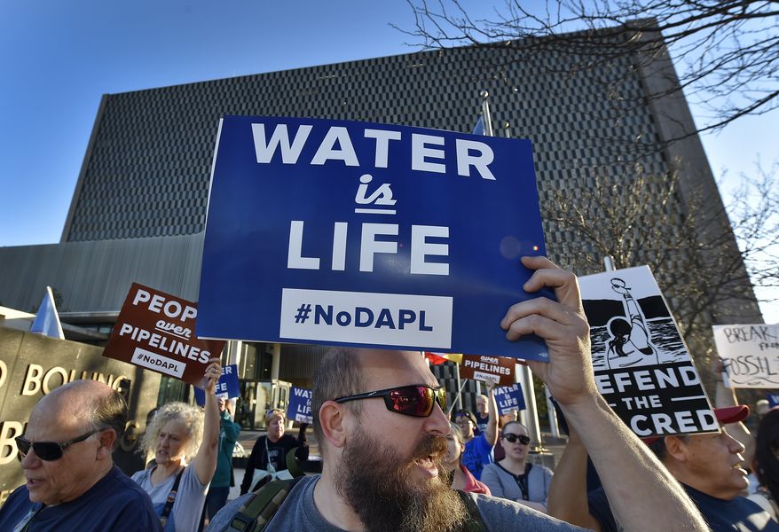 People including Steve Cramer, center, protest the Dakota Access pipeline project in front of the Richard Bolling Federal Building on Tuesday, Nov. 15, 2016, in downtown Kansas City, Mo. The company building a $3.8 billion oil pipeline sought a federal judge's permission Tuesday to circumvent President Barack Obama's administration and move ahead with a disputed section of the project in North Dakota, as opponents held protests across the country urging it to be rejected. (Keith Myers/The Kansas City Star via AP)