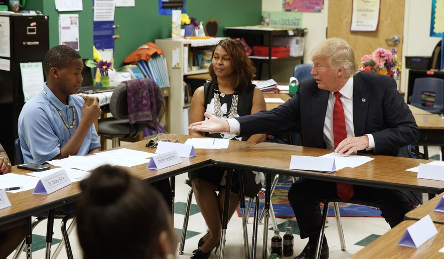 FILE - In this Sept. 8, 2016, file photo, then=Republican presidential candidate Donald Trump reaches to shake hands with Egunjobi Songofunmi during a meeting with students and educators before a speech on school choice at Cleveland Arts and Social Sciences Academy in Cleveland.  (AP Photo/Evan Vucci, File) **FILE**