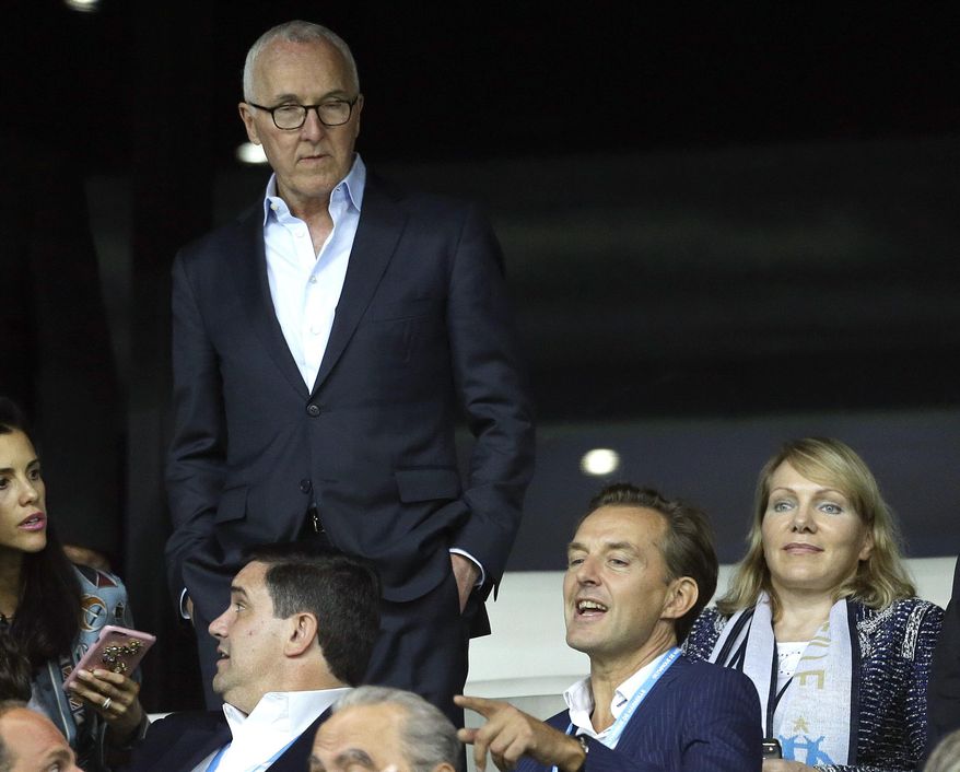 FILE - In this Sept. 18, 2016 file photo, USA's Frank McCourt, standing, is seen with former owner of Olympique Marseille Margarita Louis Dreyfus, right, in the Velodrome Stadium, in Marseille, southern France. Frank McCourt's plans to bring Marseille back to the top of French and European soccer could be undermined by local criminals. (AP Photo/Claude Paris, File)