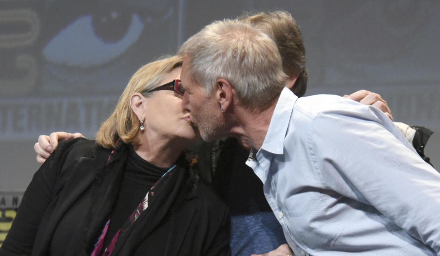 In this July 10, 2015, file photo, Carrie Fisher, left, and Harrison Ford kiss at the Lucasfilm's "Star Wars: The Force Awakens" panel on day 2 of Comic-Con International in San Diego, Calif. Fisher revealed in an interview with People magazine published online on Nov. 15, 2016, that she had an affair with Ford during the filming of the 1977 film, "Star Wars." (Photo by Richard Shotwell/Invision/AP, File) **FILE**