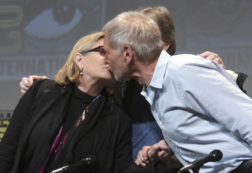 In this July 10, 2015, file photo, Carrie Fisher, left, and Harrison Ford kiss at the Lucasfilm's "Star Wars: The Force Awakens" panel on day 2 of Comic-Con International in San Diego, Calif. Fisher revealed in an interview with People magazine published online on Nov. 15, 2016, that she had an affair with Ford during the filming of the 1977 film, "Star Wars." (Photo by Richard Shotwell/Invision/AP, File) **FILE**