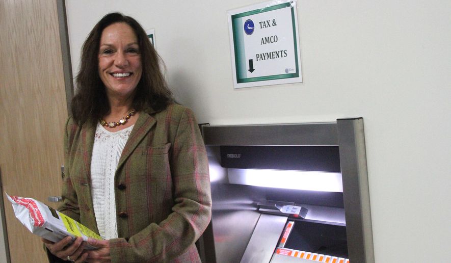 This photo taken Monday, Nov. 14, 2016, in downtown Anchorage, Alaska, shows Kelly Mazzei, revenue audit supervisor for the state of Alaska tax division, posing with a deposit safe intended for marijuana businesses to pay their taxes in cash. It's the only in-person drop-site for cash tax payments for marijuana businesses. Banking remains an issue for legal pot businesses in Alaska, since marijuana is still considered an illegal drug on the federal level. (AP Photo/Mark Thiessen)