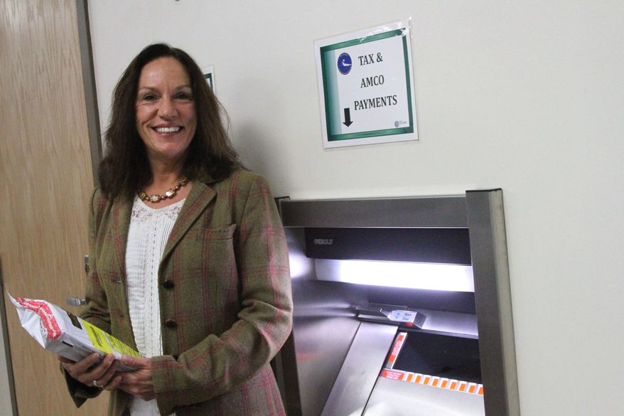 This photo taken Monday, Nov. 14, 2016, in downtown Anchorage, Alaska, shows Kelly Mazzei, revenue audit supervisor for the state of Alaska tax division, posing with a deposit safe intended for marijuana businesses to pay their taxes in cash. It's the only in-person drop-site for cash tax payments for marijuana businesses. Banking remains an issue for legal pot businesses in Alaska, since marijuana is still considered an illegal drug on the federal level. (AP Photo/Mark Thiessen)
