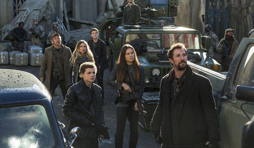 This photo provided by TNT shows, from left, Will Patton, Sarah Carter, Maxim Knight, Connor Jessup, Moon Bloodgood, Drew Roy (on the truck in the back) and Noah Wyle, in a scene from the television series, "Falling Skies." At least 35 people have been killed and many more injured since 2000 in accidents on productions outside the United States run by major studios, as well as regional companies. In 2014, a security guard was killed in Vancouver on set of the television series "Falling Skies." (James Dittiger/TNT via AP)