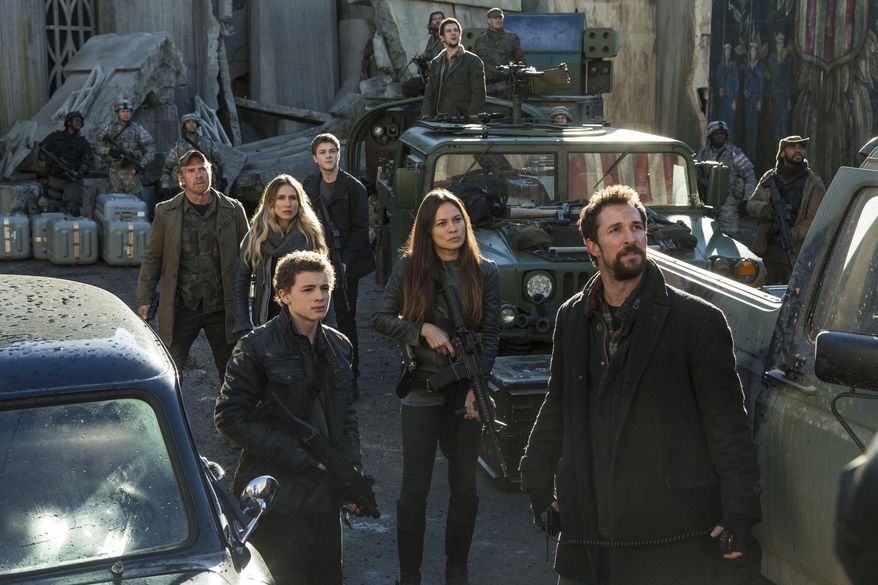 This photo provided by TNT shows, from left, Will Patton, Sarah Carter, Maxim Knight, Connor Jessup, Moon Bloodgood, Drew Roy (on the truck in the back) and Noah Wyle, in a scene from the television series, "Falling Skies." At least 35 people have been killed and many more injured since 2000 in accidents on productions outside the United States run by major studios, as well as regional companies. In 2014, a security guard was killed in Vancouver on set of the television series "Falling Skies." (James Dittiger/TNT via AP)