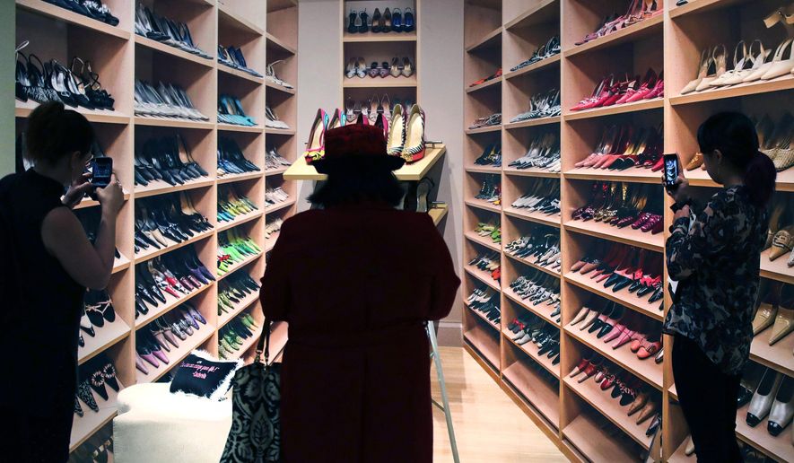 In this Tuesday, Nov. 15, 2016 photo, guests snap images of a shoe closet display at the Peabody Essex Museum in Salem, Mass. From flats to stilettos, what we put on our feet says something about who we are. That’s the premise of new exhibition in Massachusetts. “Shoes: Pleasure and Pain” opens Saturday, Nov. 19, 2016, at the Peabody Essex Museum in Salem. (AP Photo/Charles Krupa)