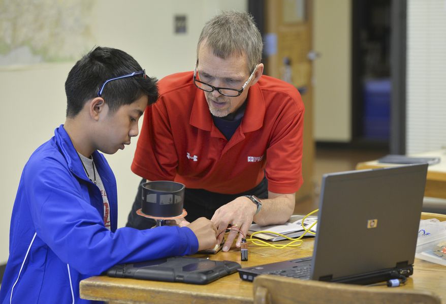 In this April 5, 2016 photo, instructor Steve Larson works with Brian Meyer, 13, on a programming project using an Arduino electronics and programming kit at St. John's Prep School in Collegeville, Minn. (Kimm Anderson/St. Cloud Times via AP)