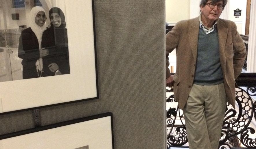 In this Wednesday, Nov. 16, 2016 photo photographer Mark Chester stands for a portrait next to images in his exhibit called The Bay State: A Multicultural Landscape -Photographs of New Americans, at the Statehouse, in Boston. Cape Cod-based Chester has produced a collection of photographs of immigrants from all over the world. (AP Photo/Denise Lavoie)