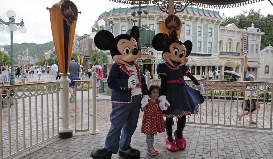 FILE - In this June 10, 2016, file photo, a girl poses with Mickey and Minnie Mouse at the Hong Kong Disneyland in Hong Kong. Hong Kong officials said Tuesday, Nov. 22, 2016 they signed an agreement for a $1.4 billion expansion of the southern Chinese city’s Disneyland theme park. The government said the plan calls for adding two new themed areas, based on the movie “Frozen” and characters from “Marvel Super Heroes,” to Hong Kong Disneyland. (AP Photo/Kin Cheung, File)