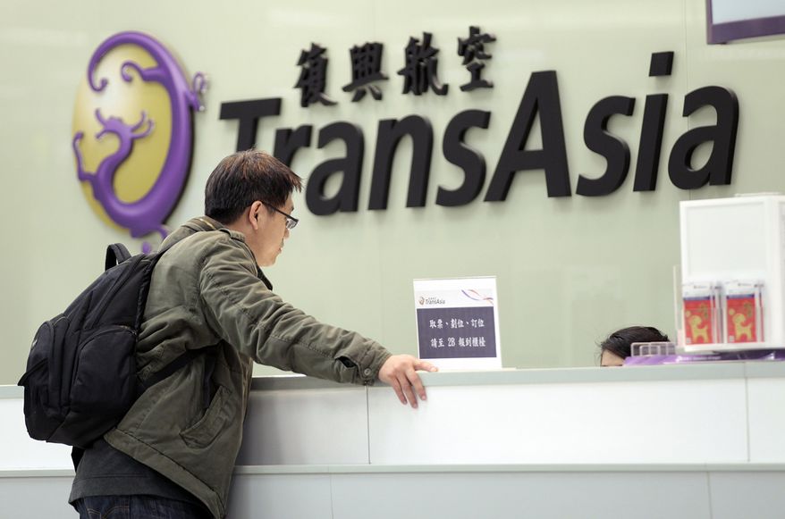 FILE- In this Saturday, Feb. 7, 2015, file photo, a passenger waits at the ticket counter of TransAsia Airways at the Songshan Airport in Taipei, Taiwan. Taiwanese airline TransAsia has announced it is shutting down following financial losses and two fatal crashes. TransAsia chairman Vincent Lin said Tuesday the airline, which served cities in China, Japan and Southeast Asia, was unable to reverse widening losses or raise additional money. (AP Photo/Wally Santana, File)