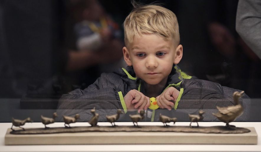 In this Nov. 21, 2016, photo, a boy clutches a toy duck as he views a sculpture depicting the classic children's story "Make Way for Ducklings" at an exhibit at the Museum of Fine Arts in Boston. The new exhibition is devoted to Robert McCloskey, the award-winning author of 1941's "Make Way for Ducklings" and other children's classics. (AP Photo/Charles Krupa)