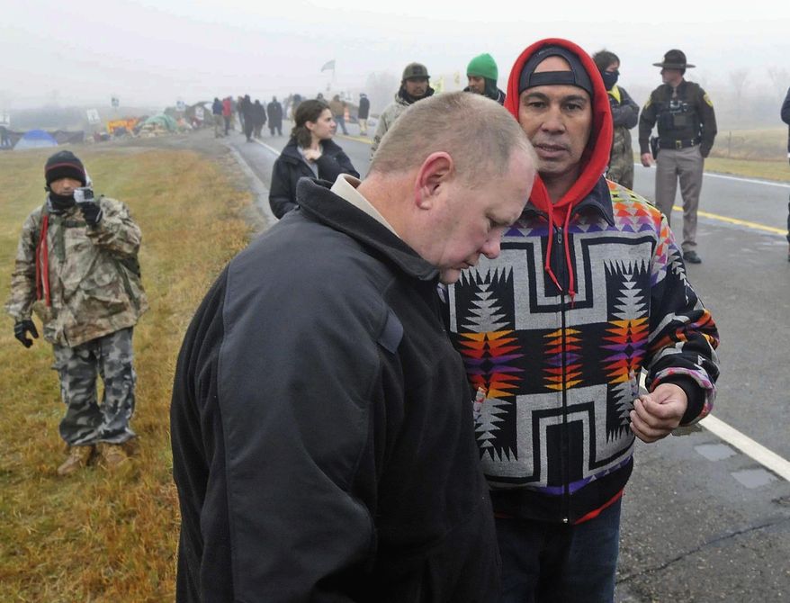 FILE - In this Oct. 26, 2016 file photo, Morton County Sheriff Kyle Kirchmeier, front, listens to Brian Wesley Horinek, of Oklahoma, outside the New Camp on Pipeline Easement in North Dakota. Kirchmeier, who has led the police response to the Dakota Access oil pipeline, is a law enforcement lifer, a veteran of the North Dakota State Patrol and National Guard before being elected to his first term as Morton County sheriff. (Tom Stromme/The Bismarck Tribune via AP, File) /The Bismarck Tribune via AP)