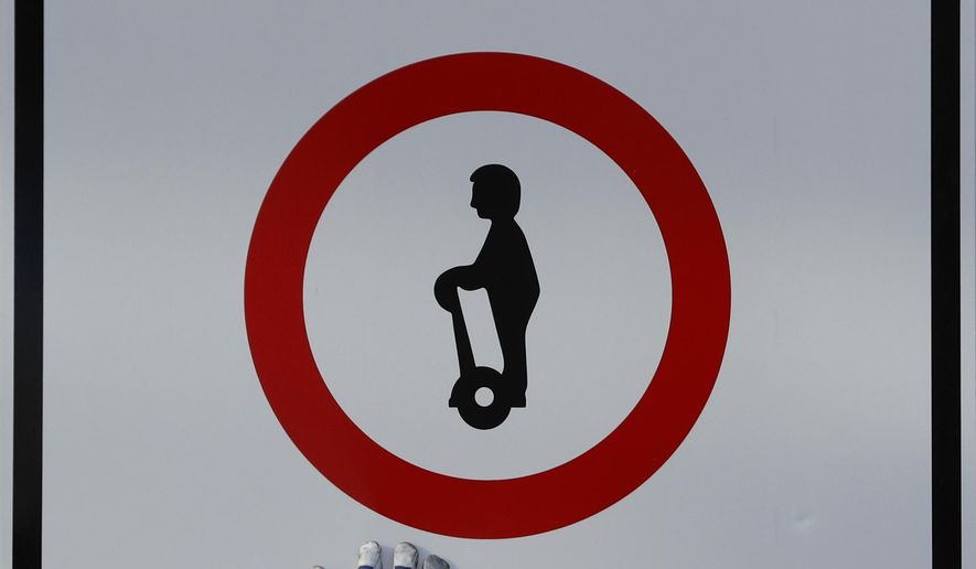 Workers adjust a sign banning the two-wheeled electric vehicles Segways downtown Prague, Czech Republic, Monday, Nov. 28, 2016. A ban on Segway scooters in Prague's historic center and some other parts of the Czech capital is one step from becoming effective. (AP Photo/Petr David Josek)