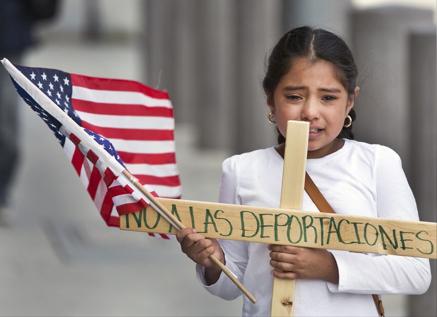 Yesenia Del Carmen 8, carries a cross reading "No to the Deportations," "as she and her grandmother join an immigrant-rights supporters "Procession of the Cross" walk, led by U.S.-born children from the Federal building to the Cathedral of Our Lady of the Angels in Los Angeles, Friday, Apr. 18, 2014. Immigrants urged the Obama administration today to stop deportations that they said are splitting up families. Del Carmen worries her father could be deported while at work. (AP Photo/Damian Dovarganes)