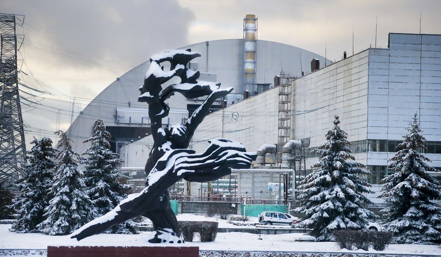 The monument to the victims of the Chernobyl tragedy is in front of a new shelter installed over the exploded reactor at the Chernobyl nuclear plant, Chernobyl, Ukraine, Tuesday, Nov. 29, 2016. A massive shelter has finally been installed over the exploded reactor at the Chernobyl nuclear plant, one of the most ambitious engineering projects in the world. (AP Photo/Efrem Lukatsky)