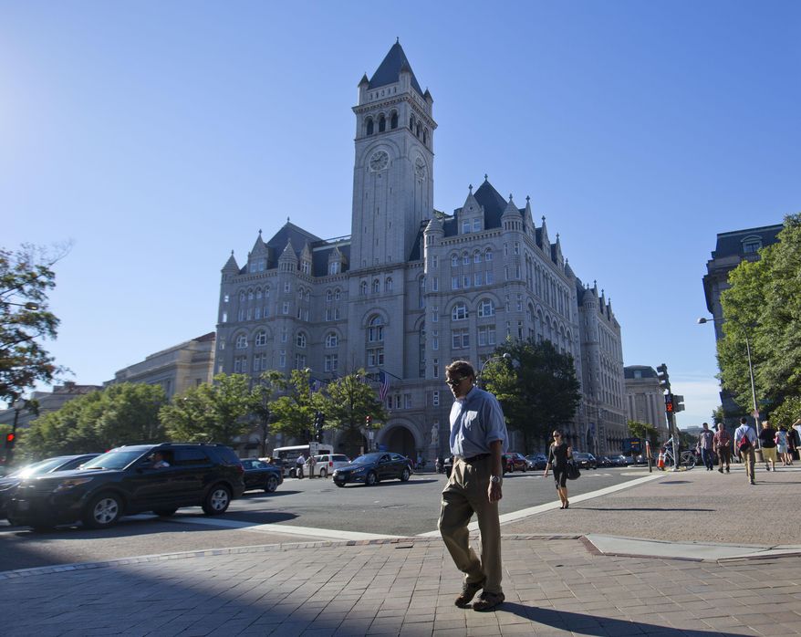 FILE - In this Monday, Sept. 12, 2016, file photo, pedestrians cross Pennsylvania Avenue across the street from the Trump International Hotel in downtown Washington. Several experts in government contract law say that President-elect Donald Trump will have to give up his stake in his prized Washington, D.C. hotel if he wants to be president. (AP Photo/Pablo Martinez Monsivais, File)