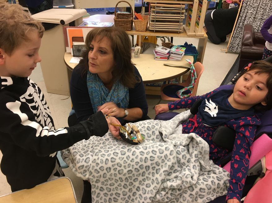 ADVANCE FOR WEEKEND EDITIONS, DEC. 3-4 - In this Nov. 17, 2016 photo, Diggory Mardock, 4, left, shows Lennah Martinez, 4, right, his art creation at the Child Family and Research Center at the University of Nevada, Reno. Lennah is one of 20 students that is part of an inclusive preschool program. (Siobhan McAndrew/The Reno Gazette-Journal via AP)