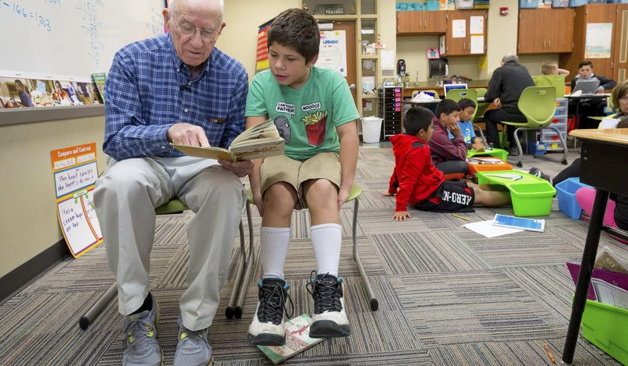 In this Thursday, Oct 13, 2016 photo, Dick Leeper, left, reads to Dominick Carroll at Roosevelt Elementary School in Council Bluffs, Iowa. The octogenarian has walked through the doors of Council Bluffs' Roosevelt Elementary almost every school day for 16 years. While his friends are enjoying retirement on the golf course, Leeper is ambling down the school hallways with a smile. (Kent Sievers/The World-Herald via AP)