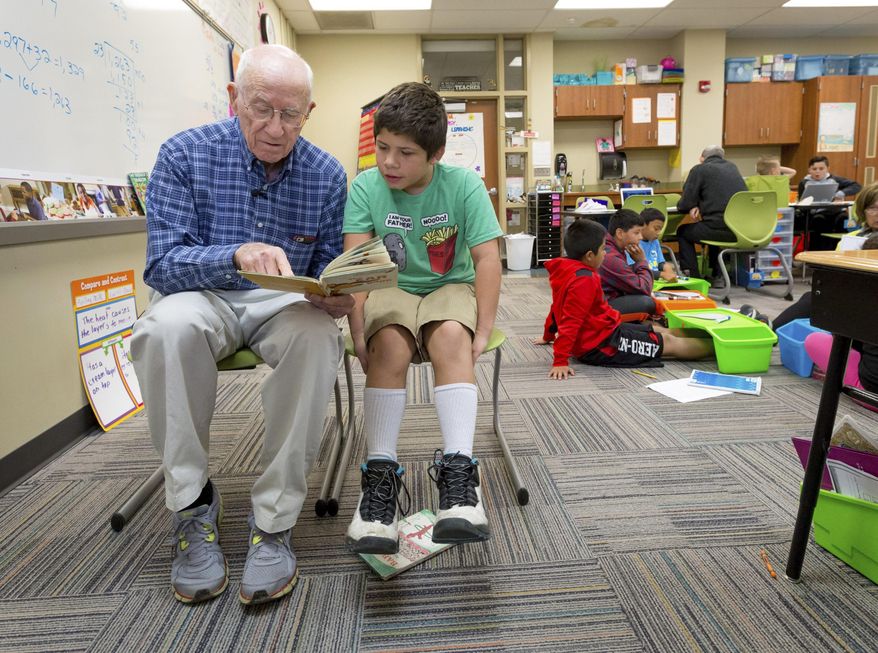 In this Thursday, Oct 13, 2016 photo, Dick Leeper, left, reads to Dominick Carroll at Roosevelt Elementary School in Council Bluffs, Iowa. The octogenarian has walked through the doors of Council Bluffs' Roosevelt Elementary almost every school day for 16 years. While his friends are enjoying retirement on the golf course, Leeper is ambling down the school hallways with a smile. (Kent Sievers/The World-Herald via AP)