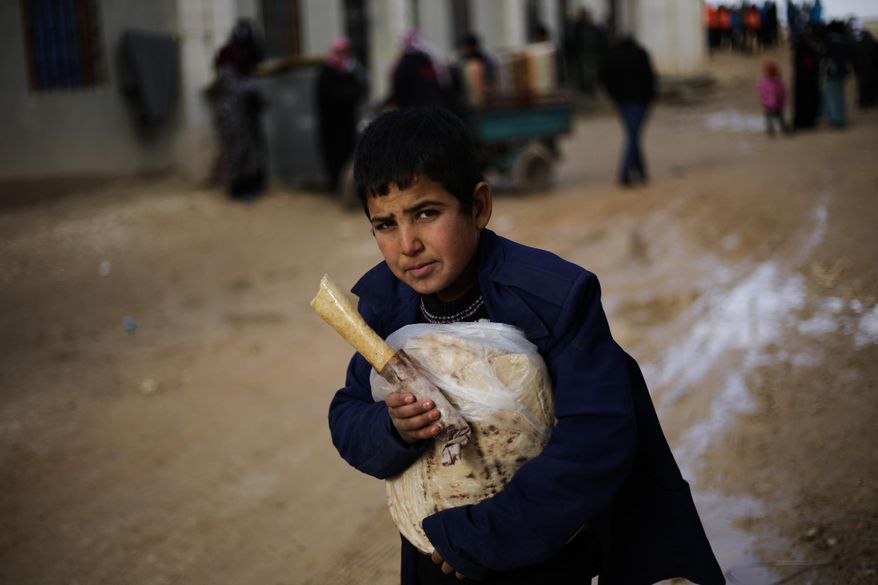 A Syrian boy displaced with his family from eastern Aleppo holds a sandwich and bread bag in the village of Jibreen south of Aleppo, Syria, Saturday, Dec. 3, 2016. Aid agencies say that more than 30,000 people have fled rebel-held eastern neighborhoods of Aleppo that have been under tight siege since July. Over the past two weeks, government forces launched an offensive in which they regained control of nearly half areas that had been held by insurgents in their deepest push since the city became contested in July 2012.(AP Photo/Hassan Ammar)