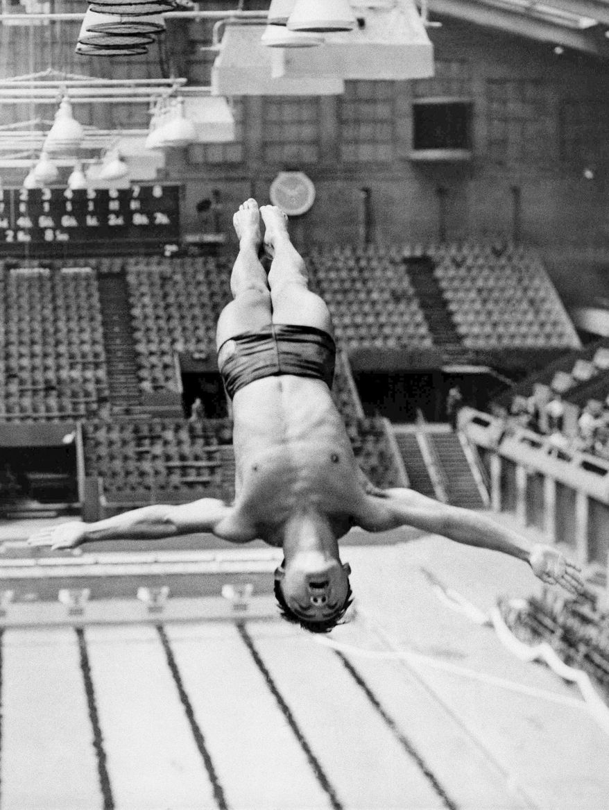 FILE - Int his July 27, 1948, file photo, Sammy Lee, member of the U.S. Olympic diving team, dives from the top of the diving tower during training at the London Olumpics at the Empire Pool in Wembley, England. Lee, a two-time Olympic gold medal-winning diver who later mentored four-time Olympic diving champion Greg Louganis, died Friday, Dec. 2, 2016, of pneumonia in Newport Beach, Calif., the University of Southern California said Saturday, Dec. 3. He was 96. (AP Photo/Laurence Harris, File)
