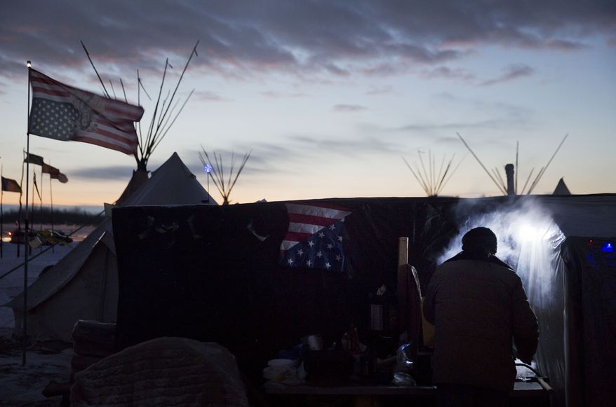 Lonnie Hamilton, a Muskogee Creek Native American from Oklahoma, hovers over the steam of a lamb stew at the Oceti Sakowin camp where people have gathered to protest the Dakota Access oil pipeline in Cannon Ball, N.D., on Dec. 2. (Associated Press)