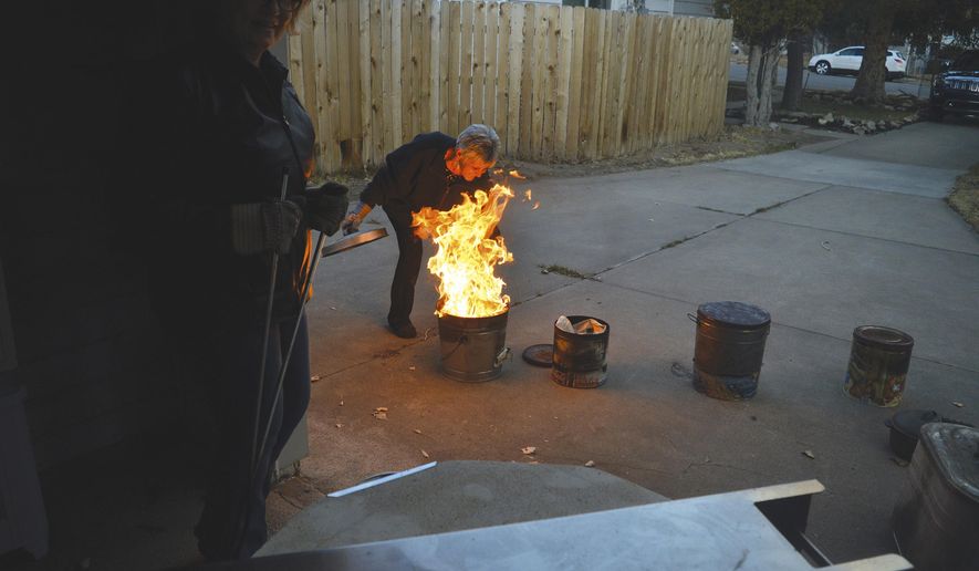 In a Nov. 14, 2016 photo, Susann Ward gets ready to cap the gushing flames after a piece of Raku pottery is dropped into the fuel of newspaper and sawdust in Rawlins, Wyo. Raku is a form of pottery that first came out of Japan, a word that means “enjoyment.” (Iain Woessner/The Rawlins Daily Times via AP)