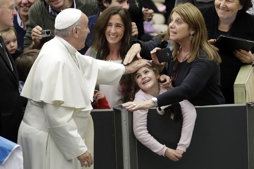Pope Francis caresses a girl as he arrives for his weekly general audience, in the Pope Paul VI hall, at the Vatican, Wednesday, Dec. 7, 2016. (AP Photo/Andrew Medichini)