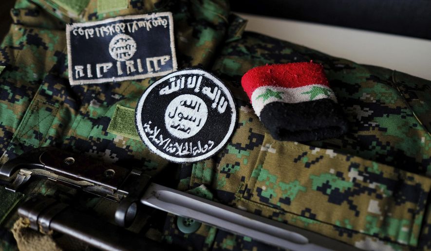 In this Dec. 2, 2016 photo, a pair of Daesh, or ISIS, patches, a wrist band featuring Syrian government markings and a bayonet collected from the battlefield in Syria are arranged atop on of Freeman Stevenson&#39;s YPG camouflage uniforms arranged for a photograph in Saratoga Springs, Utah. Stevenson volunteered for combat alongside the Kurdish militia and said he wanted to fight the Islamic State. (Spenser Heaps/The Deseret News via AP)
