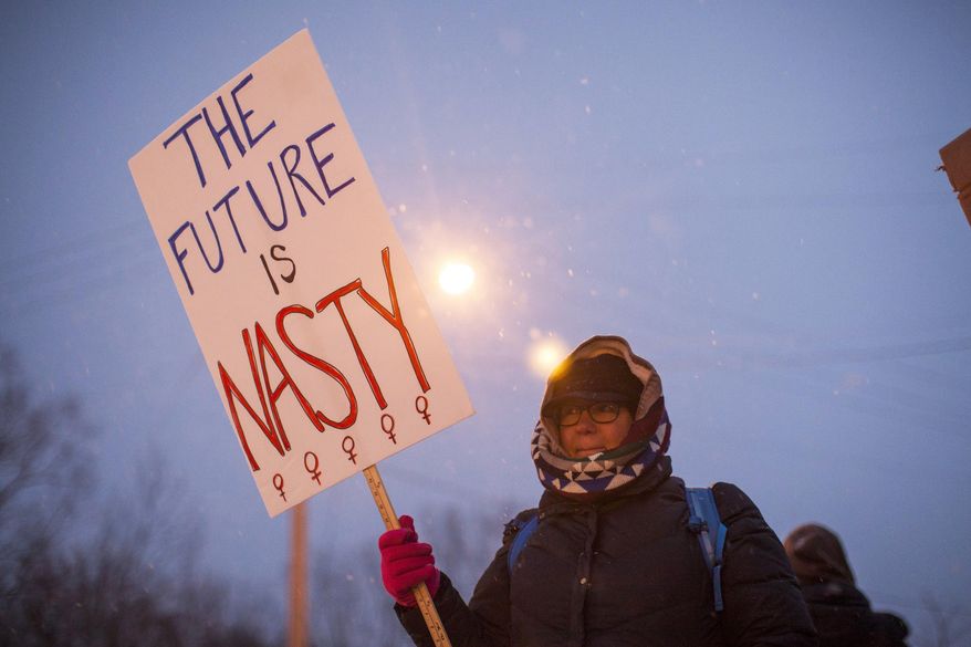 Kathy, a protester from Grand Rapids, holds a sign that reads "The Future is Nasty" at the corner of West River Drive and Turner Avenue before President-elect Donald Trump's visit to the DeltaPlex in Walker, Mich., on Friday, Dec. 9, 2016. (Allison Farrand/The Grand Rapids Press-MLive.com via AP)