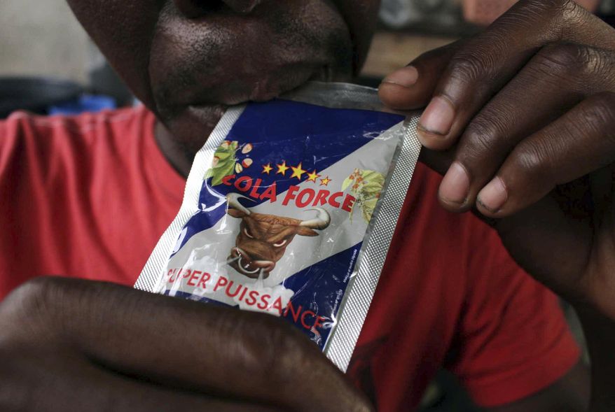 In this photo taken on Sunday, Nov. 13, 2016, a man bites on a plastic sachets containing alcohol in the city of Abidjan, Ivory Coast. Each morning at dawn, taxi driver Rene Kouame stops by his neighborhood bar in Abidjan for a potent pick-me-up: two plastic sachets of "Che Guevara," a drink of spiced rum and a host of chemicals that costs 100 CFA francs, or about 15 U.S. cents. (AP Photo/Diomande Ble Blonde)