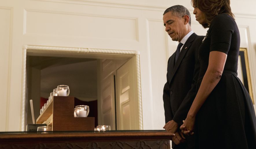 President Barack Obama and first lady Michelle Obama observe a moment of silence in honor of the Newtown shooting victims, in the Map Room of the White House in Washington, Saturday, Dec. 14, 2013, on the one year anniversary of the tragedy. (AP Photo/Jacquelyn Martin)