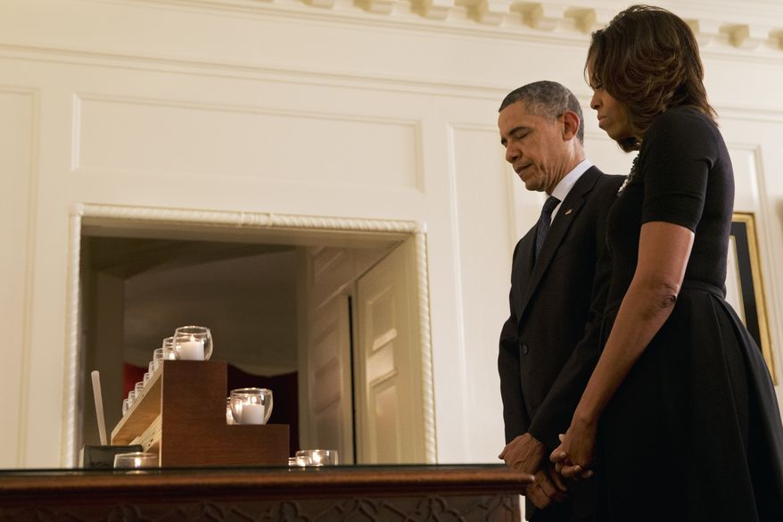 President Barack Obama and first lady Michelle Obama observe a moment of silence in honor of the Newtown shooting victims, in the Map Room of the White House in Washington, Saturday, Dec. 14, 2013, on the one year anniversary of the tragedy. (AP Photo/Jacquelyn Martin)