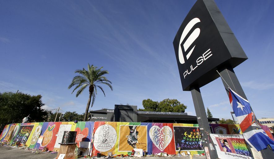 In this Wednesday, Nov. 30, 2016 photo, artwork and signatures cover a fence around the Pulse nightclub, scene of a mass shooting, in Orlando, Fla. (AP Photo/John Raoux)