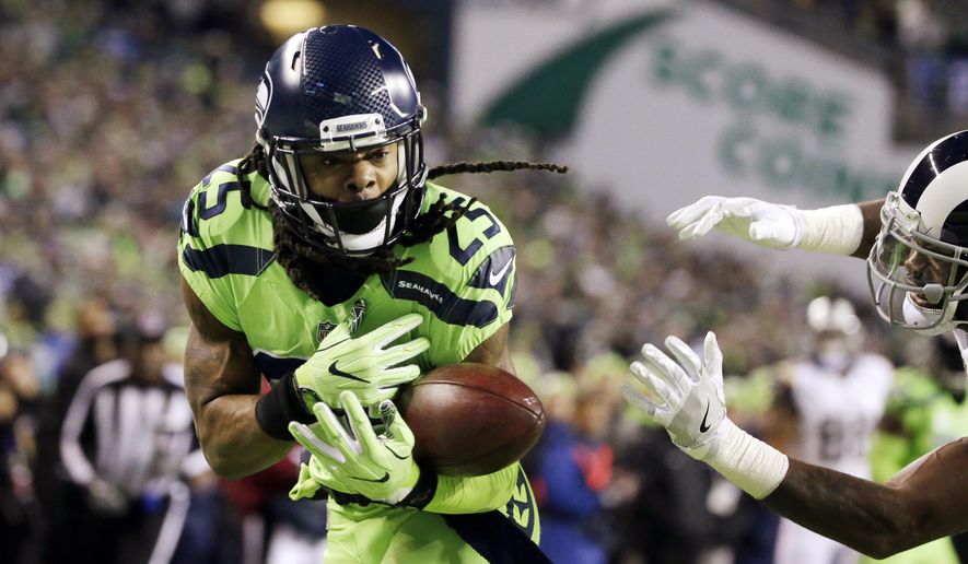 Seattle Seahawks cornerback Richard Sherman, left, bobbles a pass intended for Los Angeles Rams wide receiver Kenny Britt, right, in the first half of an NFL football game, Thursday, Dec. 15, 2016, in Seattle. (AP Photo/Elaine Thompson)
