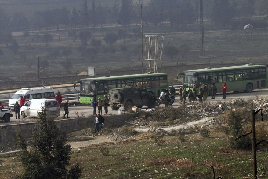 In this photo released by the Syrian official news agency SANA, green government buses carry residents evacuating from eastern Aleppo, Syria, Friday, Dec. 16, 2016. The Syrian government suspended evacuations from eastern Aleppo just hours after they resumed on Friday, saying that rebels had opened fire on a convoy of evacuees at a crossing point with the enclave, state TV reported. (SANA via AP)