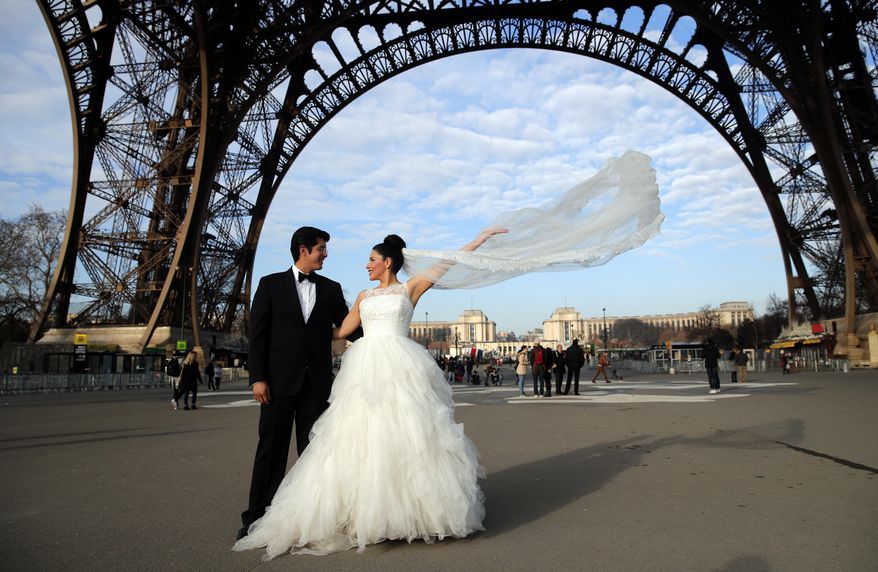 Rodrigo and Nancy of Mexico pose for a photographer under the Eiffel Tower as they are on honeymoon in Paris, Friday, Dec. 16, 2016. (AP Photo/Christophe Ena)