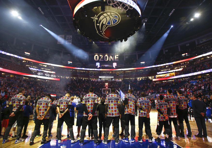 Orlando Magic players stand for the national anthem while wearing colorful shirts in honor of Craig Sager, a television sportscaster who passed away earlier in the week, before an NBA basketball game against the Brooklyn Nets in Orlando, Fla., on Friday, Dec. 16, 2016. (AP Photo/Reinhold Matay)