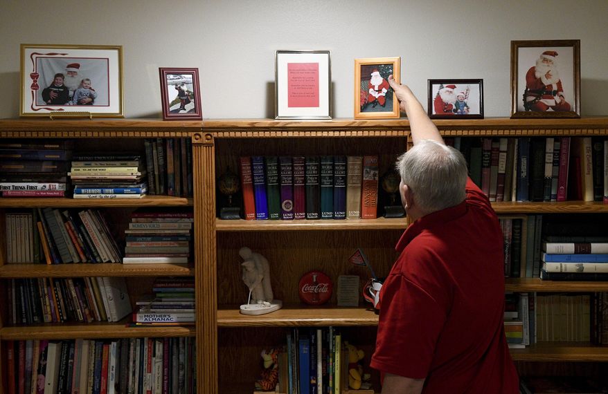 ADVANCE FOR WEEKEND EDITIONS, DEC. 17-18 - In this Friday, Dec. 9, 2016 photo, Tom Carter puts pictures of himself dressed as Santa Claus back on a shelf at his home in Orem, Utah. Tom is a part of the second generation of the three generations of Santa Clauses in the Carter family. (Isaac Hale/The Daily Herald via AP)