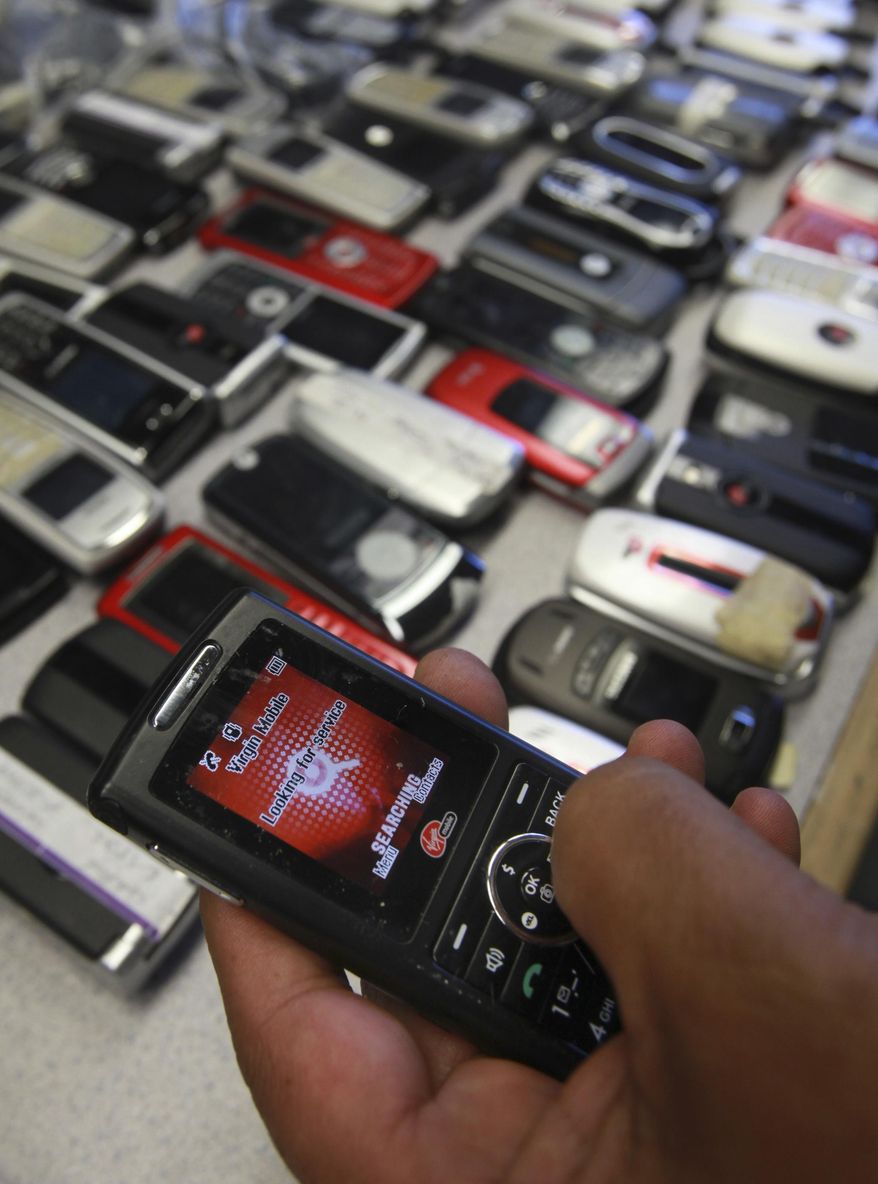 FILE - In this photo taken April 10, 2009, file photo Correctional Officer Jose Sandoval, inspects one of the more than 2,000 cell phones confiscated from inmates at California State Prison, Solano in Vacaville, Calif. California is installing nearly 1,000 sophisticated metal detectors and scanners at its prisons in its latest attempt to thwart the smuggling of cellphones. (AP Photo/Rich Pedroncelli, File)