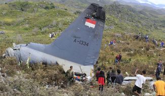 Rescuers collect personal belongings of the victims of an Indonesian Air Force plane that crashed in the mountainous area in Wamena, Papua province, Indonesia Sunday, Dec. 18, 2016. The Hercules C-130 transport plane crashed in bad weather in the easternmost province, killing all people on board. (AP Photo/Gerry Kossay)