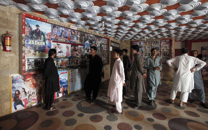 Pakistani cinema-goers look at photos displayed at a local cinema in Karachi, Pakistan, Sunday, Dec. 18, 2016. A Pakistan Film Exhibitors Association official says local cinema owners have decided to resume screening of Indian movies after a two month self-imposed ban. (AP Photo/Fareed Khan)