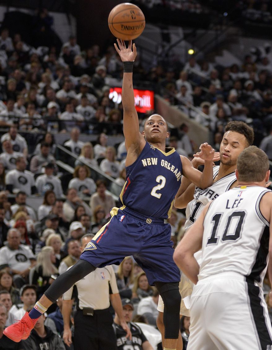 New Orleans Pelicans guard Tim Frazier (2) shoots against San Antonio Spurs' David Lee (10) and Kyle Anderson during the first half of an NBA basketball game, Sunday, Dec. 18, 2016, in San Antonio. (AP Photo/Darren Abate)